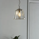 Polished nickel pendant light with clear glass shade in a modern hallway.