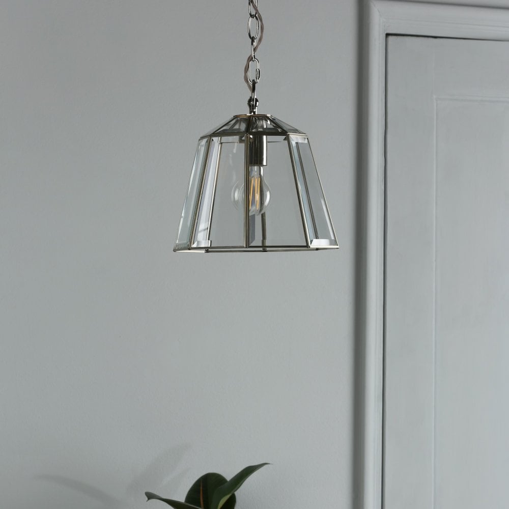 Polished nickel pendant light with clear glass shade hangs in a modern hallway.