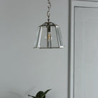 Polished nickel pendant light with clear glass shade hangs in a modern hallway.