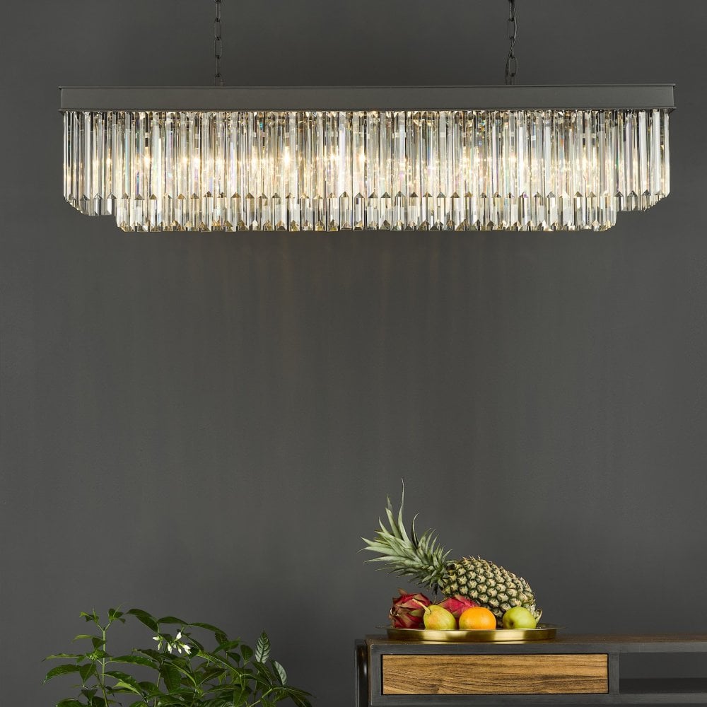 A rectangular crystal chandelier hanging above a dark wooden console table with fruit.