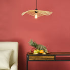 A ceiling light over a side table with fruit and a sofa chair in a room with a red wall.