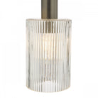 Close-up of an illuminated ribbed glass pendant light with antique brass fitting.