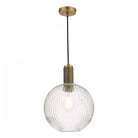A close-up of a clear, ribbed glass globe pendant light with a brass fixture.