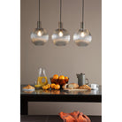 Three ribbed glass globe pendant lights illuminate a breakfast table setting.