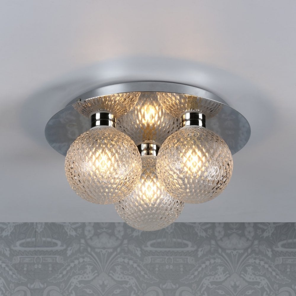 A ceiling light with three textured glass orb shades and a polished chrome base, lit on a patterned ceiling.