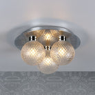 A ceiling light with three textured glass orb shades and a polished chrome base, lit on a patterned ceiling.