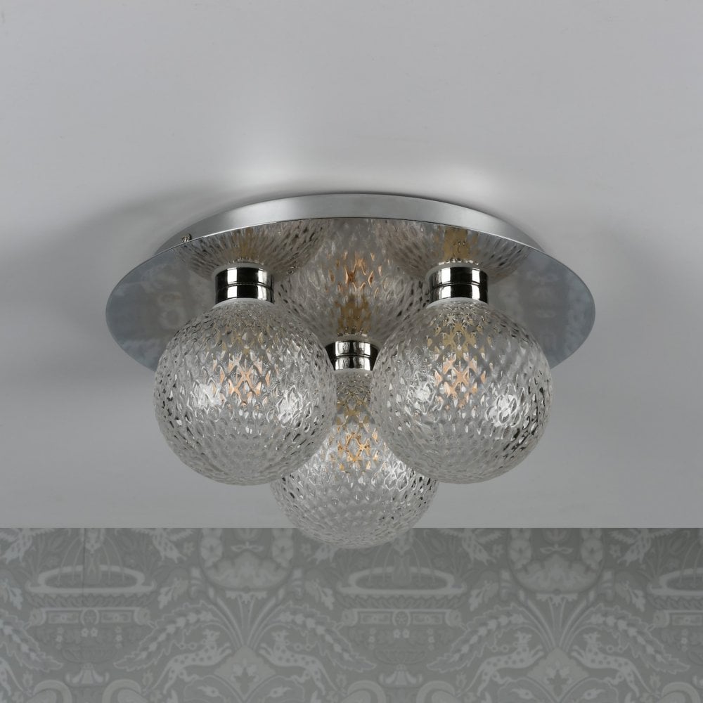 A ceiling light with three textured glass orb shades and a polished chrome base, unlit on a patterned ceiling.