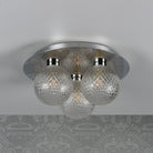 A ceiling light with three textured glass orb shades and a polished chrome base, unlit on a patterned ceiling.