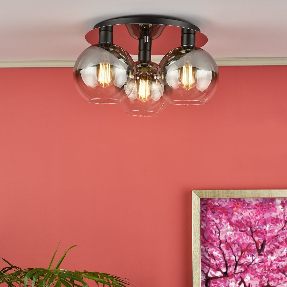 A modern ceiling light with three smoked glass globes illuminates a vibrant coral room.