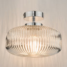 A close-up view of the ribbed glass flush ceiling light with a chrome fixture, lit.