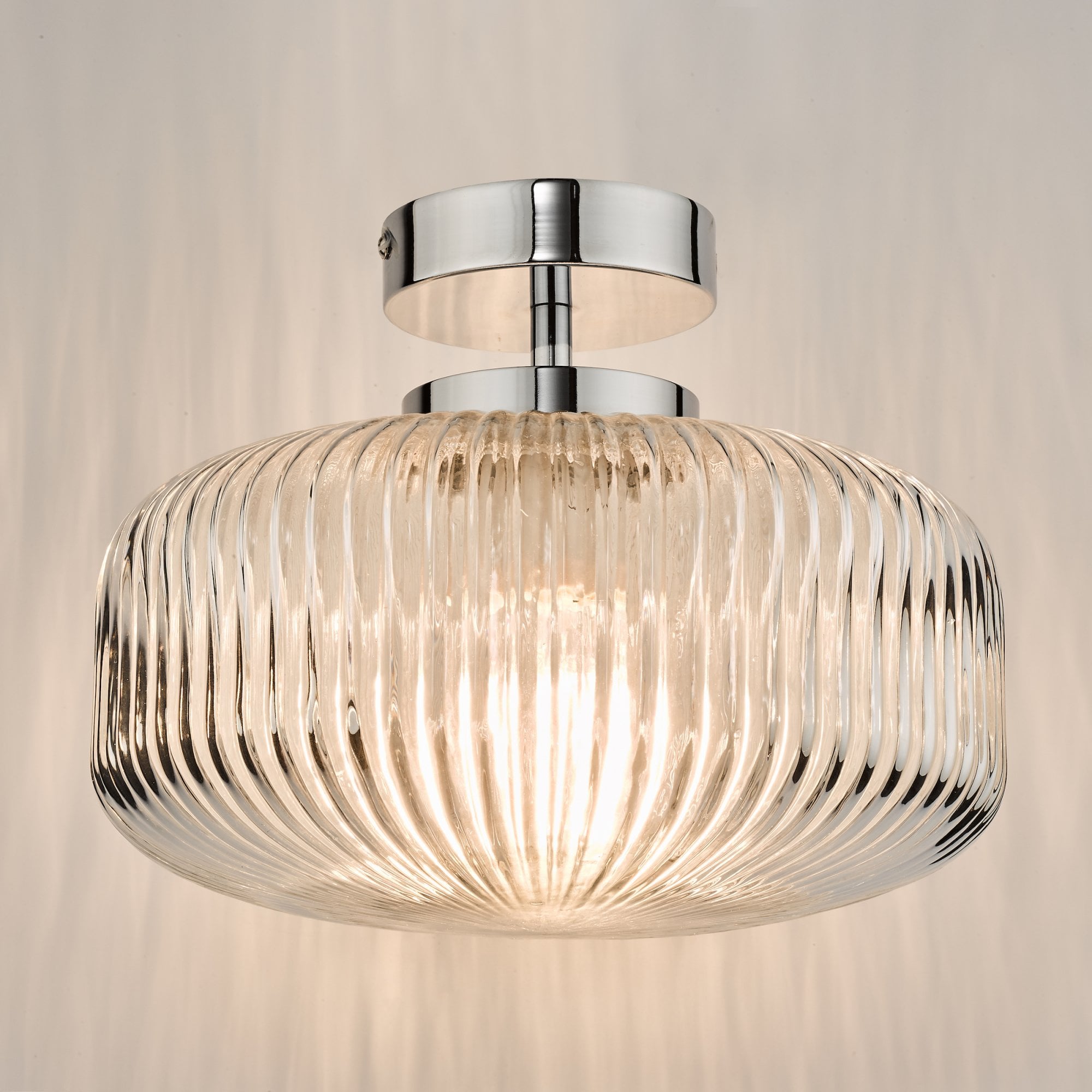 A close-up view of the ribbed glass flush ceiling light with a chrome fixture, lit.