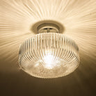 A close-up, bottom-up view of the ribbed glass flush ceiling light, lit.