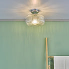 The ribbed glass flush ceiling light installed in a room with green walls.