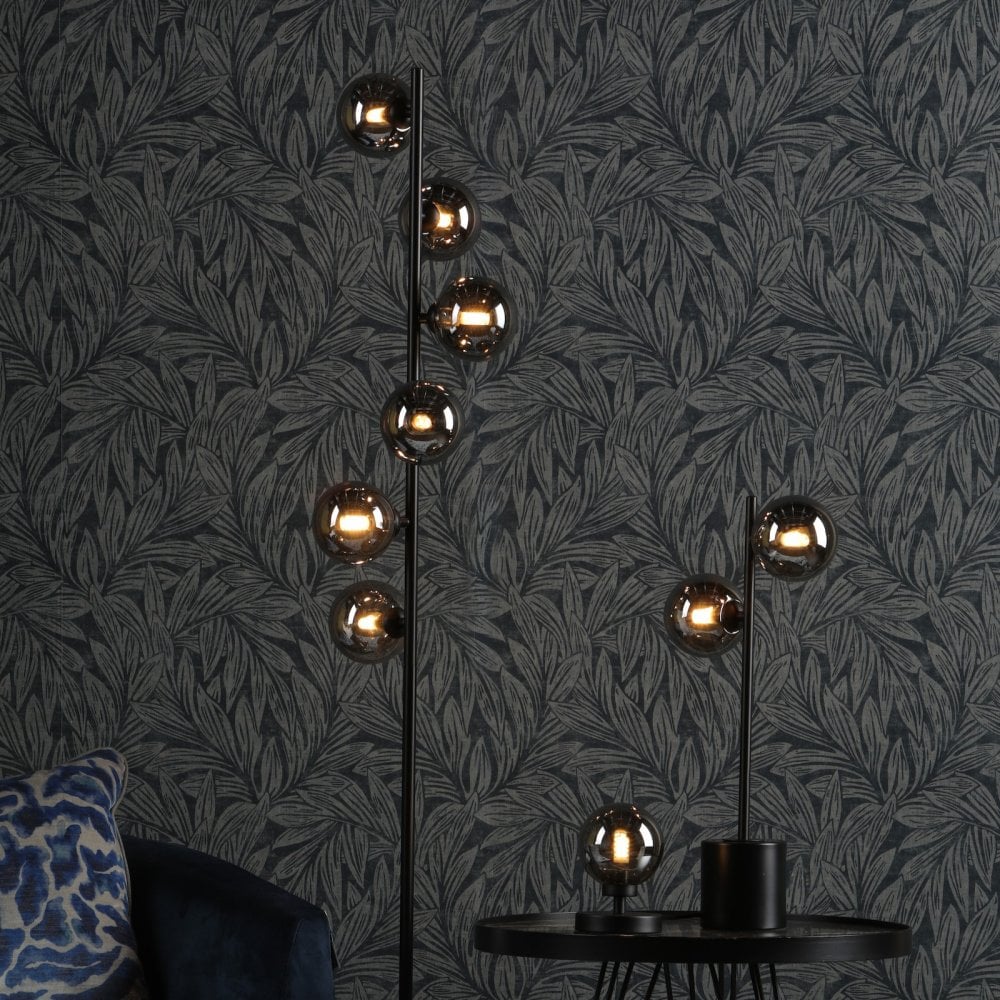 Floor and table lamps with smoked glass spheres illuminating a dark botanical wallpaper.