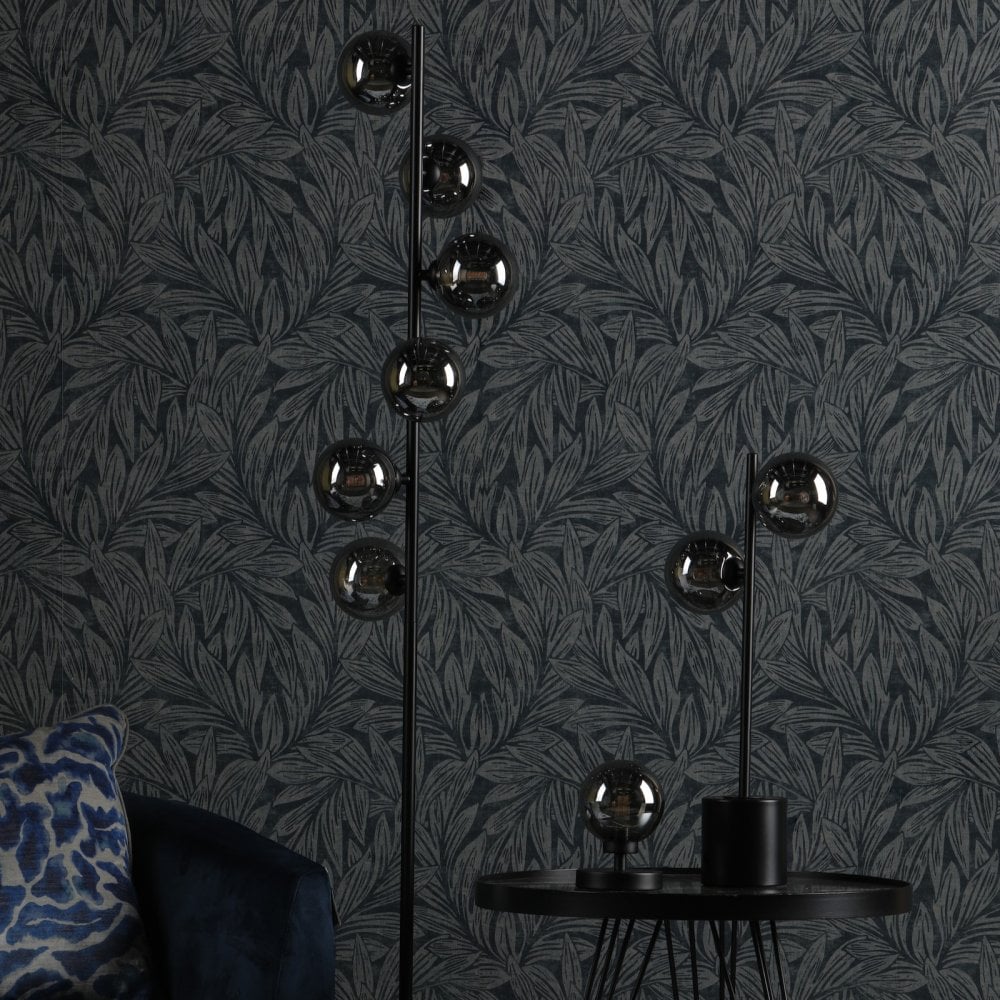 Floor and table lamps with smoked glass spheres in a room with dark botanical wallpaper.