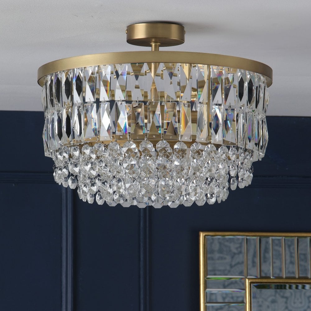 Crystal chandelier against a dark blue wall with a gold framed mirror below.