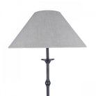 The top half of a classic floor lamp with a dark base and a light-colored tapered shade.
