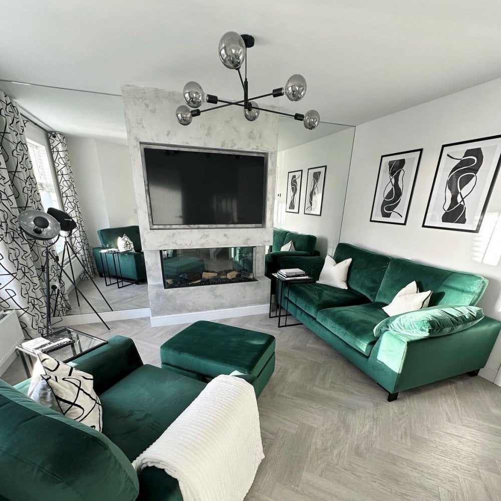 A modern living room with a black sputnik chandelier and green sofas.