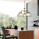 A five-arm chandelier illuminating a modern kitchen island with chairs.