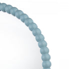 Close-up of the light blue beaded frame of a round mirror.