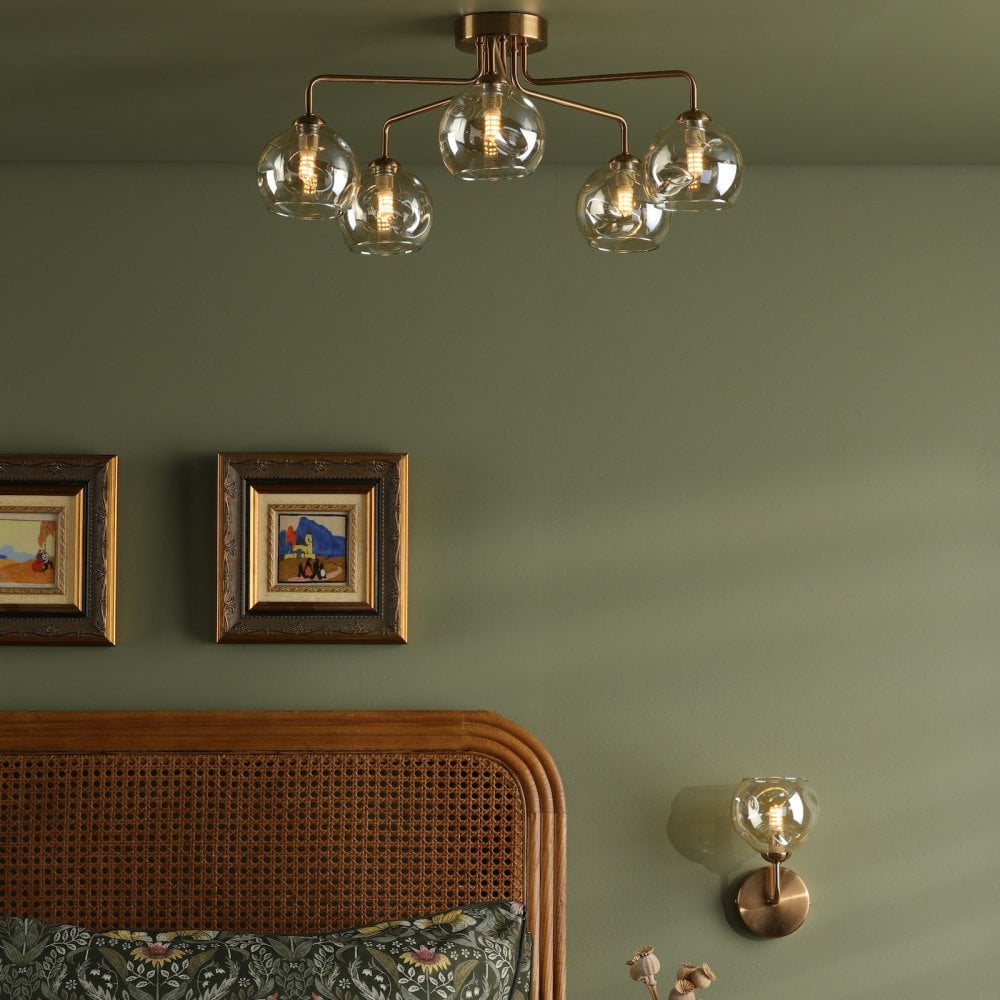 A bedroom with a ceiling light and wall light, both featuring amber glass shades.