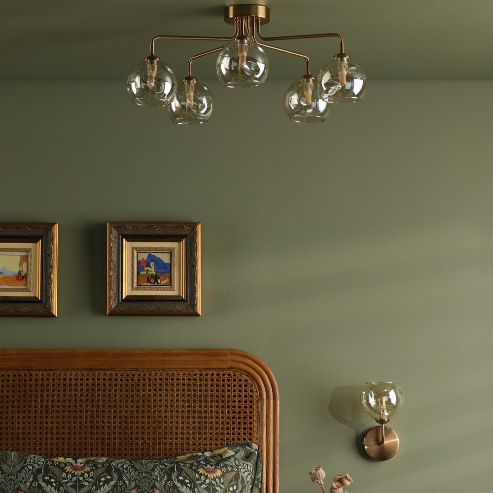 A bedroom with a ceiling light and wall light, both featuring amber glass shades.