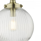 Close-up of a ribbed glass globe pendant light with brass accents, showing the texture and bulb.