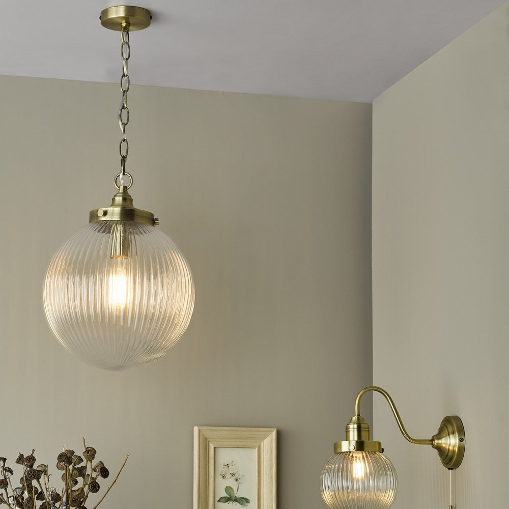 A ribbed glass globe pendant light and matching wall light with brass accents illuminate a room.