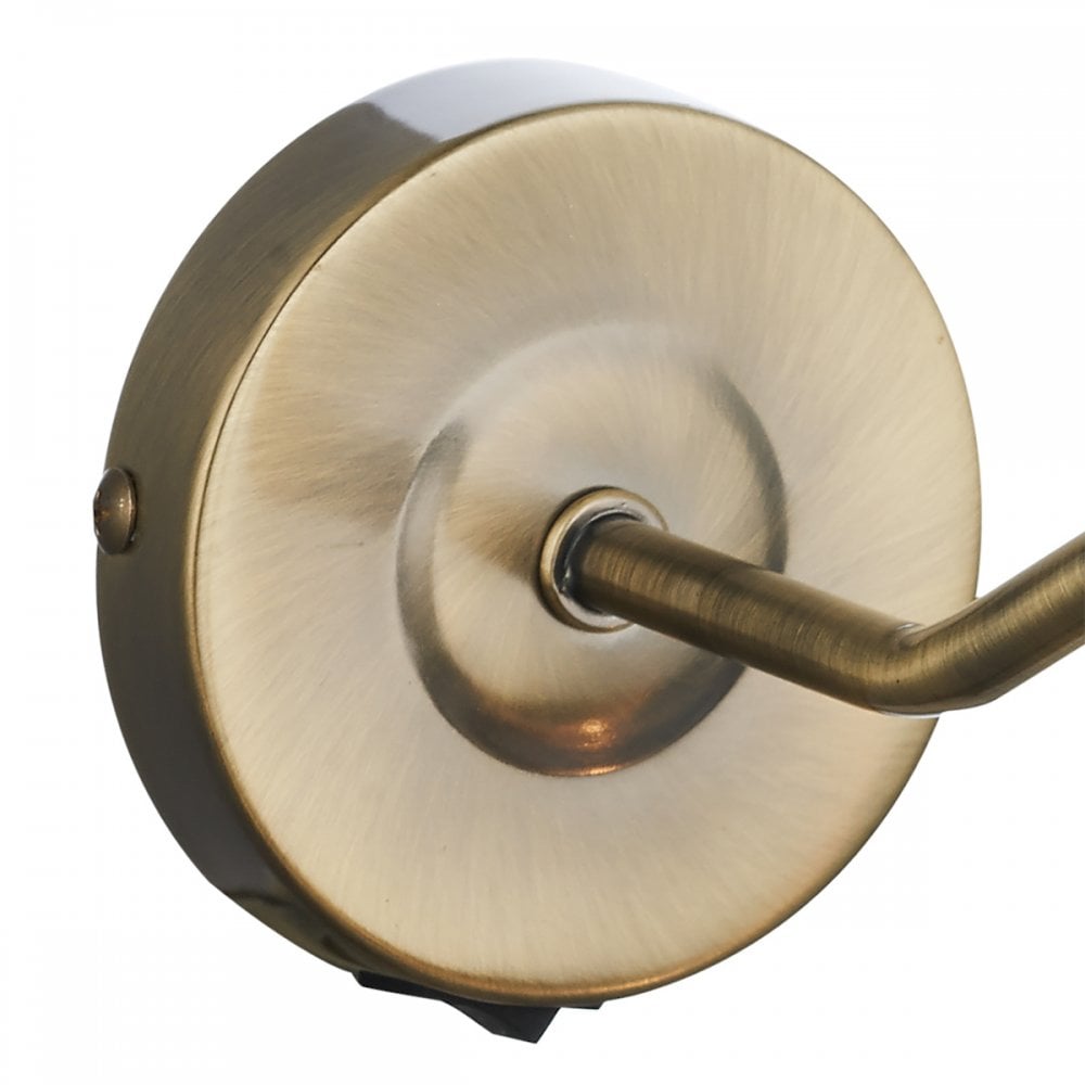 A close-up of the brass wall-mounting plate of a picture light.