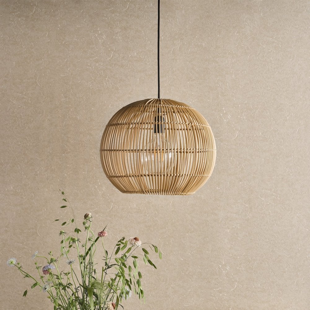 A round, light brown wicker pendant light illuminates a room with a light-colored wall.
