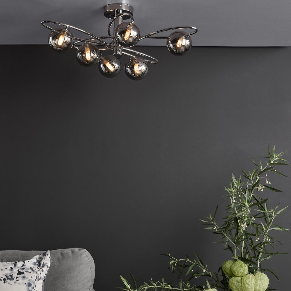 A modern ceiling light with six smoked glass orbs on chrome swirls in a grey living room.
