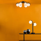 Modern ceiling light in a room with a bright orange wall and a table lamp.