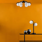 Stylish ceiling fixture and table lamp against a bold orange wall, creating a modern ambiance.