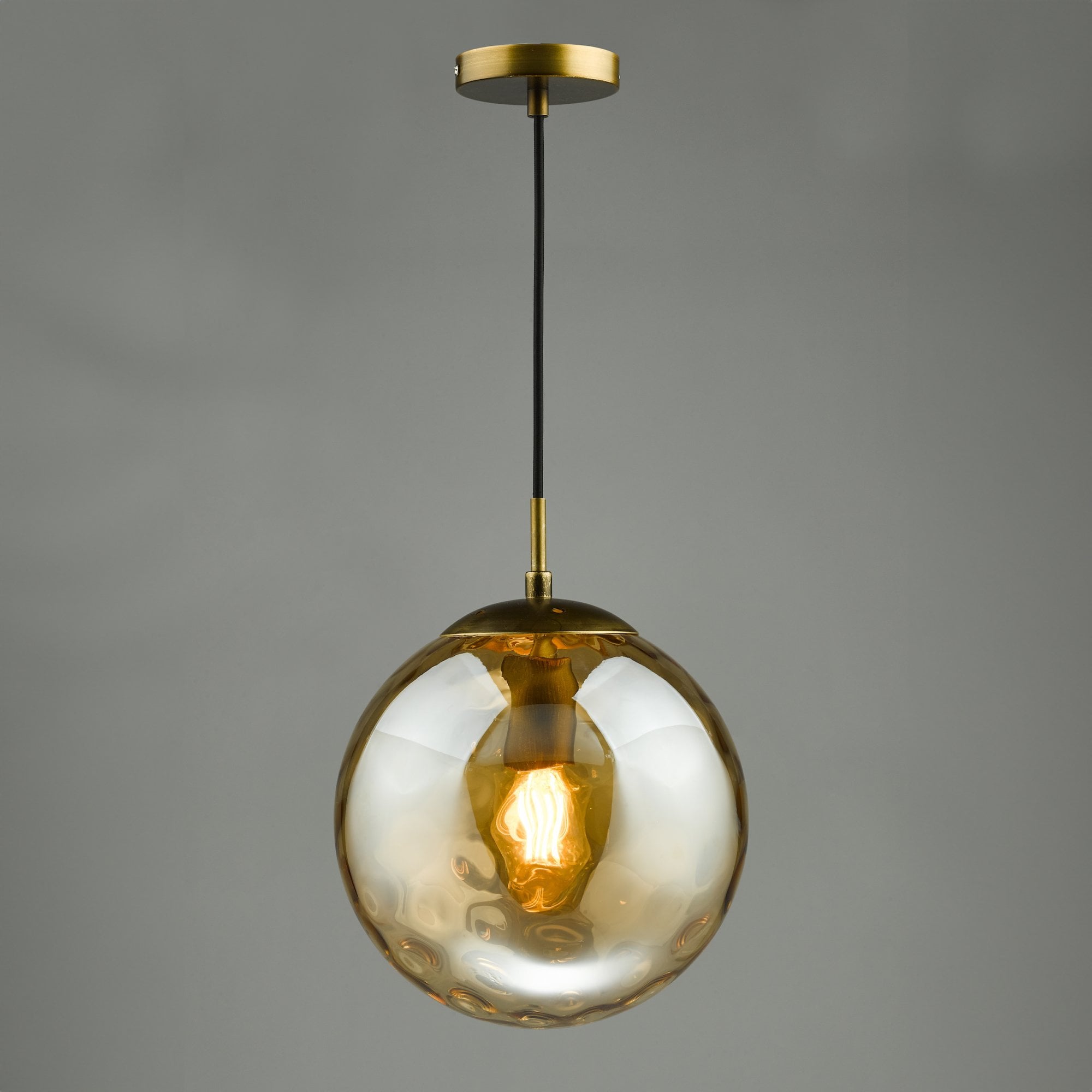 A hanging pendant light featuring an amber textured glass globe and a brass fitting.