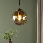 A close-up of a hanging amber glass pendant light illuminating a room.