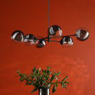 A modern black chandelier with six glass globe shades, half clear and half ribbed silver.