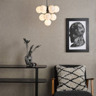 Modern chandelier with ten illuminated white globes in a living room setting.