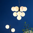 Illuminated modern black chandelier with ten white globes against a blue background.