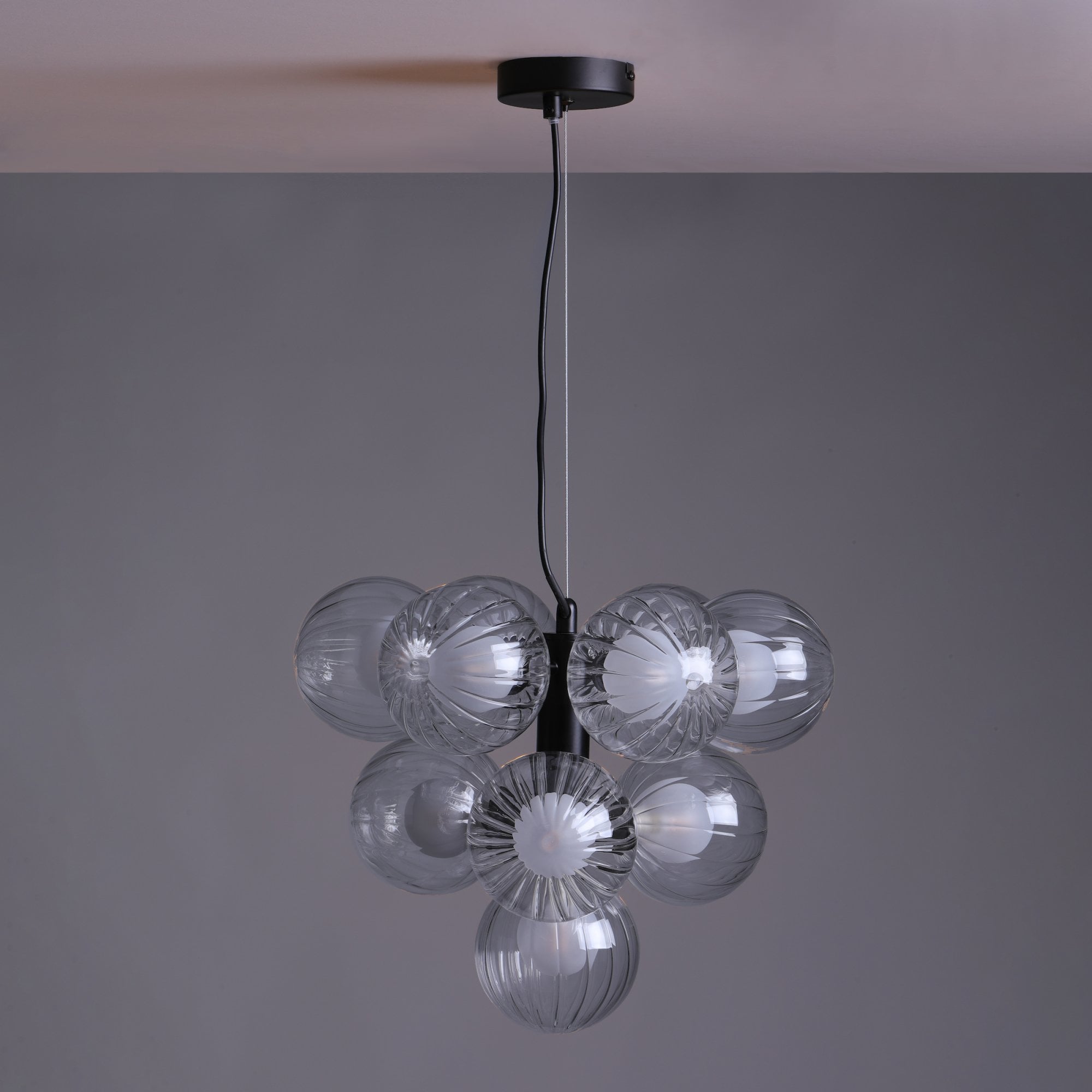 Modern chandelier with seven clear glass globes and a black ceiling mount, unlit.