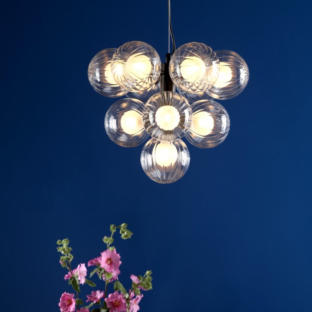 Modern chandelier with seven lit clear glass globes, black mount, and pink flowers.