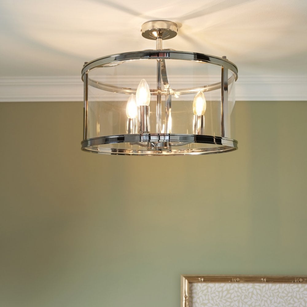 Polished chrome semi-flush ceiling light with clear glass shade, glowing warmly.