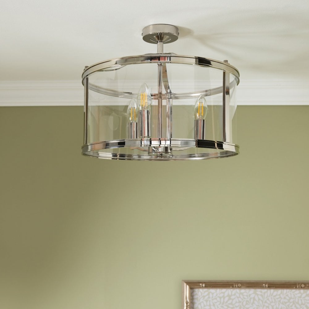 Semi-flush chrome ceiling light with clear glass and warm glowing bulbs, on a green ceiling.