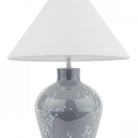 A white tapered lampshade on a grey base with white flowers on a white background.
