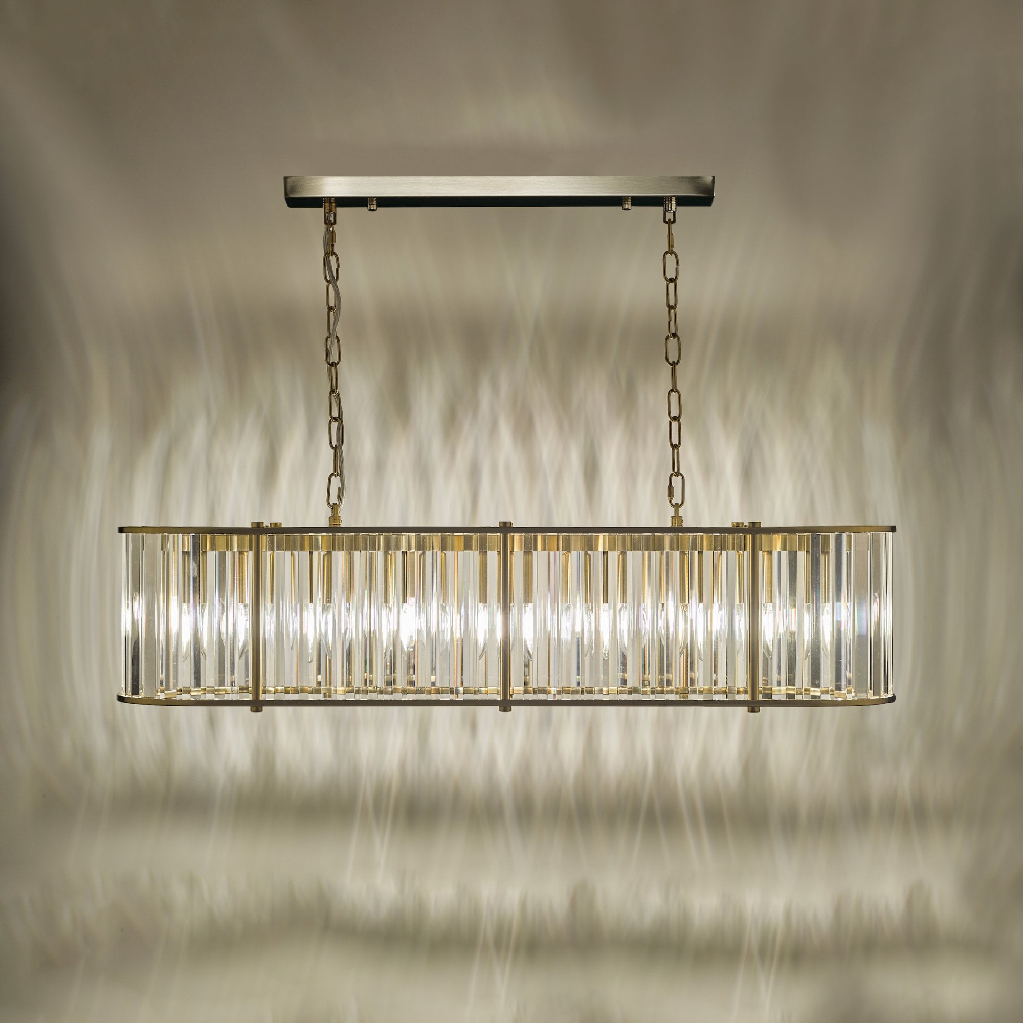 An illuminated rectangular chandelier casting light patterns on a warm-toned wall.