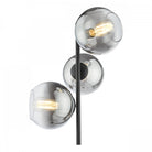 Close-up of the floor lamp's three spherical smoked glass shades with illuminated bulbs.