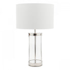 A glass and metal table lamp with a white lampshade on a white background.