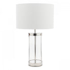 A glass and metal table lamp with a white lampshade on a white background.