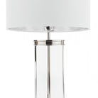Close-up of a glass and metal table lamp with a white lampshade.