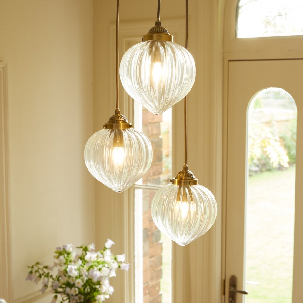 Three ribbed glass pendant lights with brass fittings brighten a cozy room.