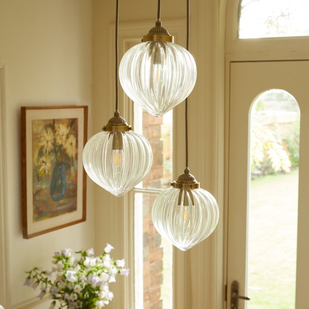 Three ribbed glass pendant lights with brass fittings add elegance to a home interior.